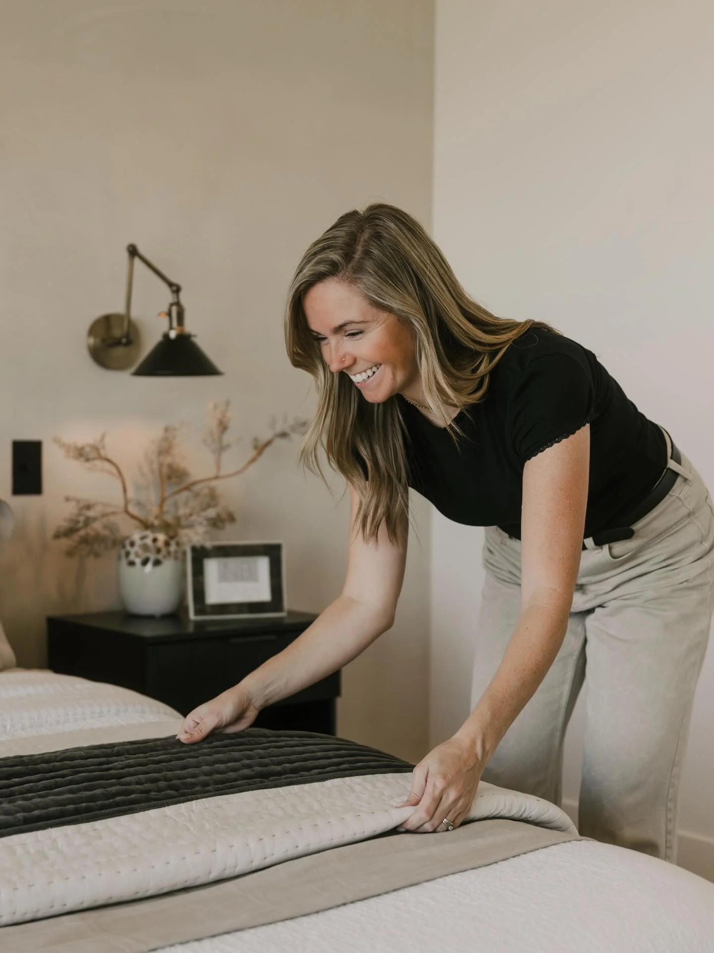 NaTasha Brittney smiling while styling a neutral layered bed